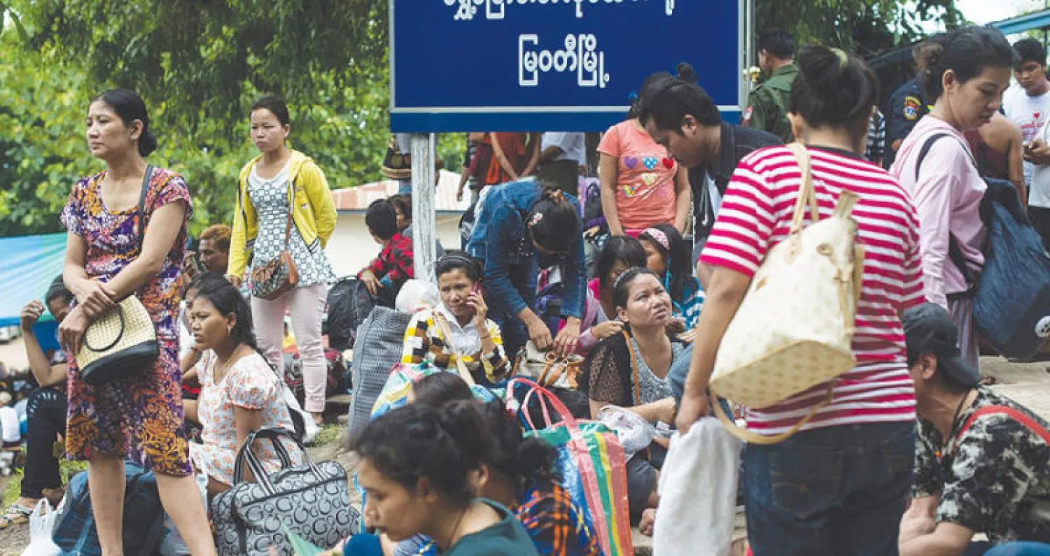 مهاجرون من بورما ينتظرون حافلات في مركز مياوادي الحدودي بين تايلاند وبورما لتعيدهم إلى بلادهم (أ.ف.ب)