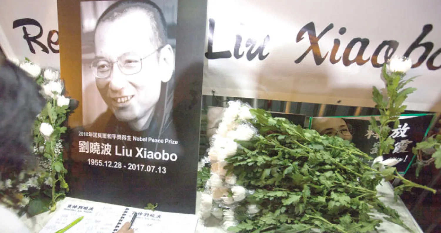 مؤيدون للمعارض الصيني ليو شياوبو الذي توفي أمس بالسرطان يضعون الزهور أمام مكتب الاتصال الصيني في هونغ كونغ (إ.ب.أ)