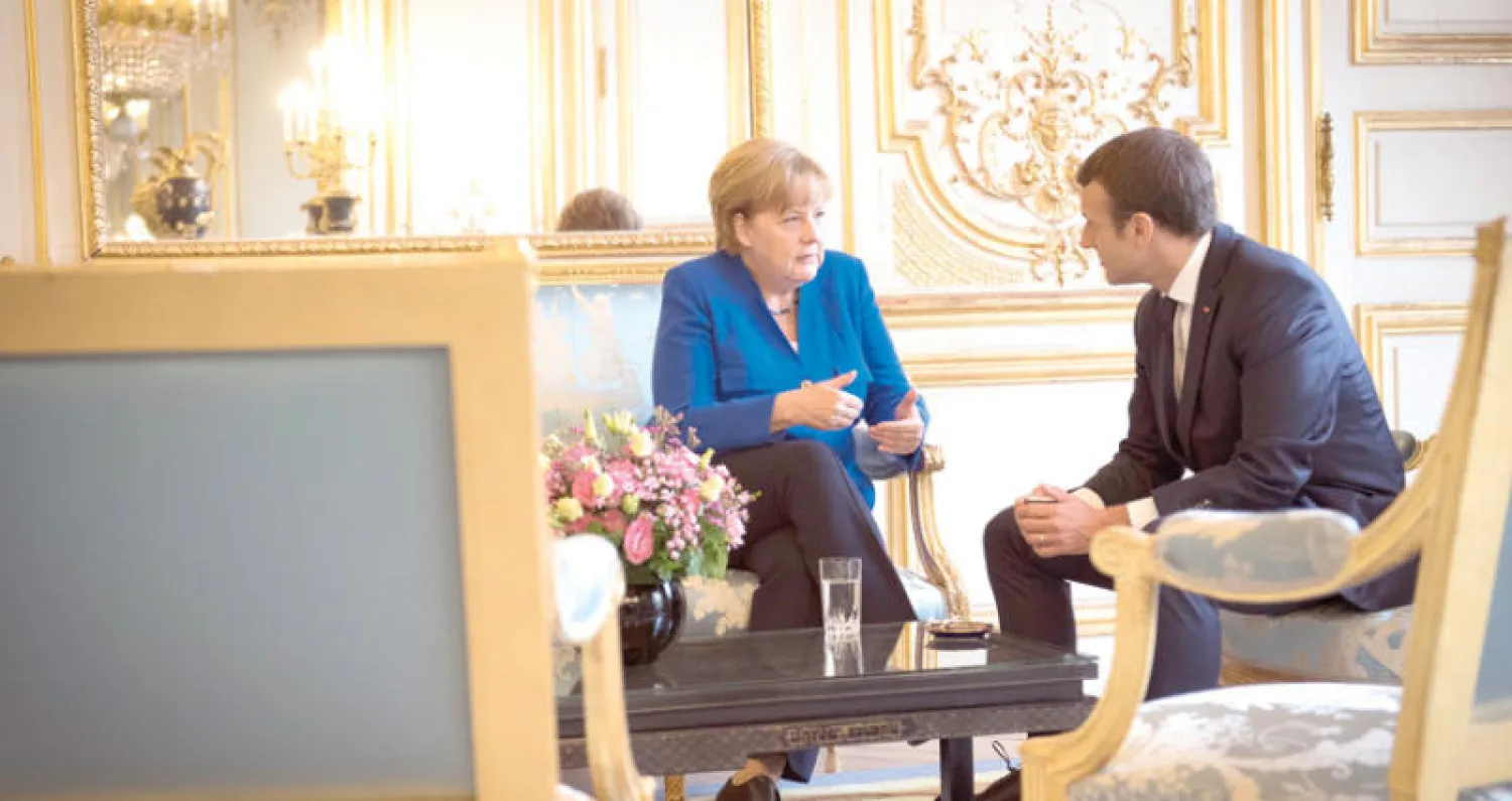 المستشارة الألمانية أنجيلا ميركل والرئيس الفرنسي إيمانويل ماكرون خلال اجتماع في قصر الإليزيه أمس (إ.ب.أ)