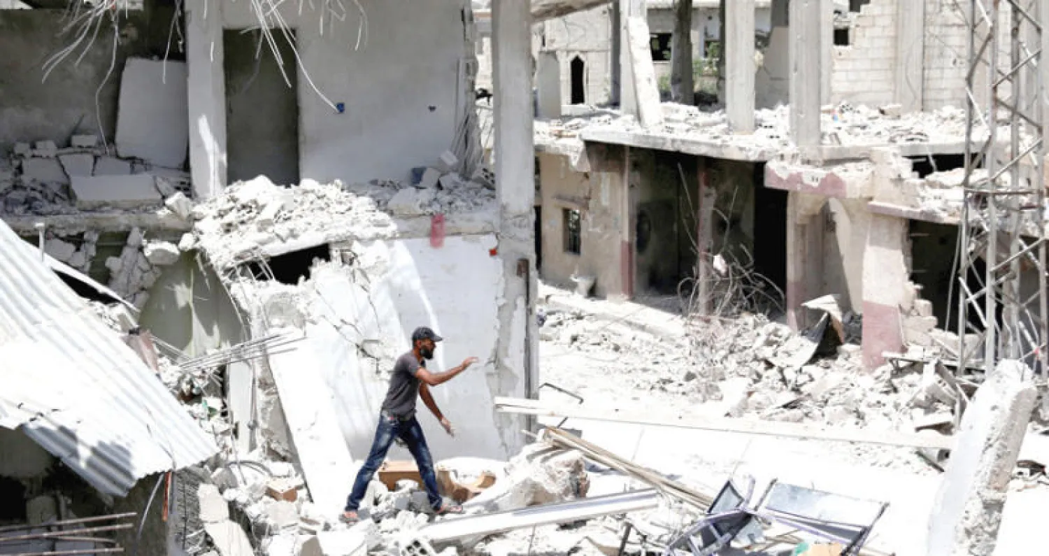 يبحث عن مقتنياته بين أنقاض مبنى مدمر في درعا (رويترز)