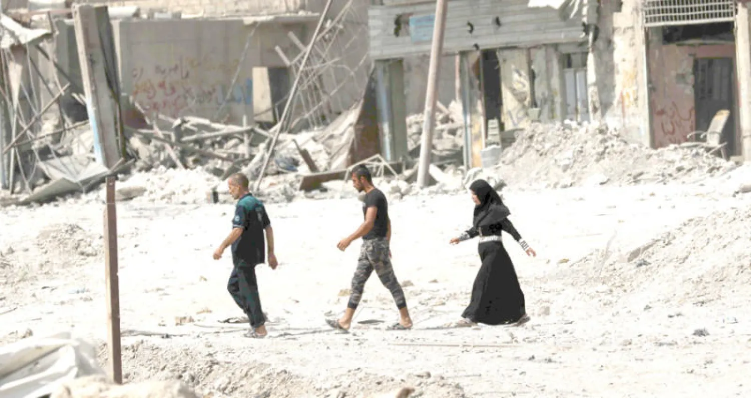 عراقيون في شارع مدمر غرب الموصل أول من أمس (أ.ف.ب)