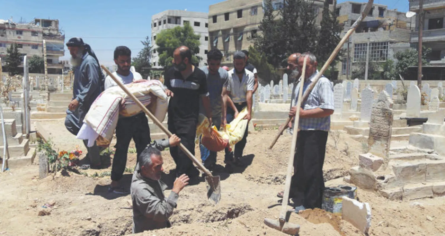 سكان قرية الحزة في الغوطة الشرقية لدمشق يستعدون لدفن طفلين من ضحايا الغارات الجوية أمس (أ.ف.ب)