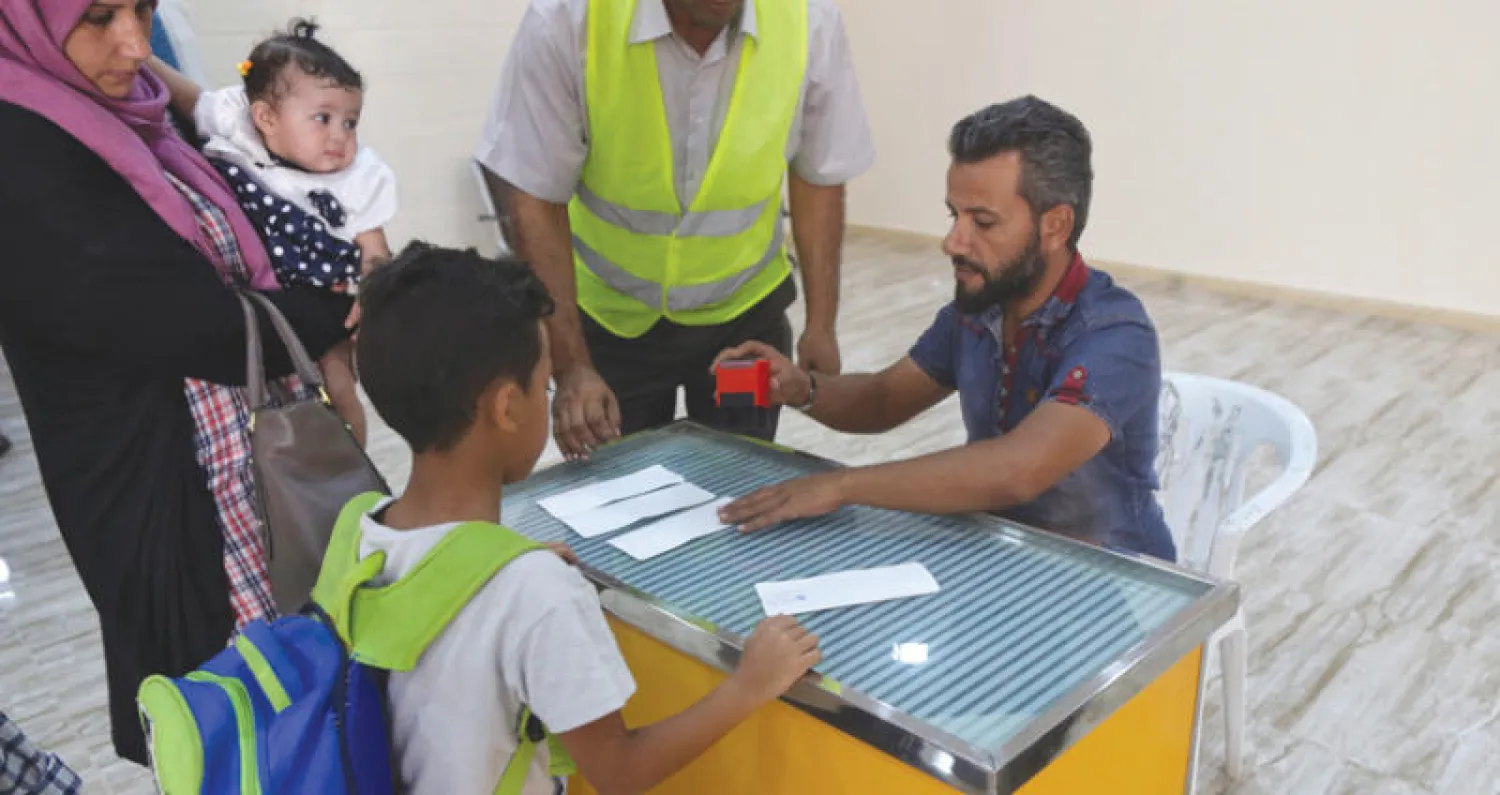 موظف في مطار بنينا (بنغازي) يختم وثائق مسافرين عبر المطار بعد إعادة فتحه أول من أمس (رويترز)