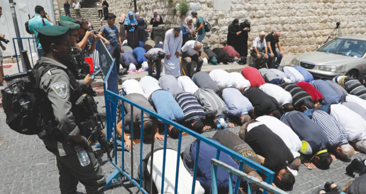 فلسطينيون مسلمون يؤدون الصلاة أمام باب الأسباط في القدس القديمة في ظل حراسات إسرائيلية مشددة