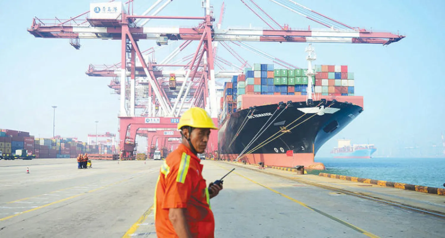 عامل في ميناء كينغداو بشرق الصين يراقب باخرة شحن وهي راسية في الميناء (أ.ف.ب)