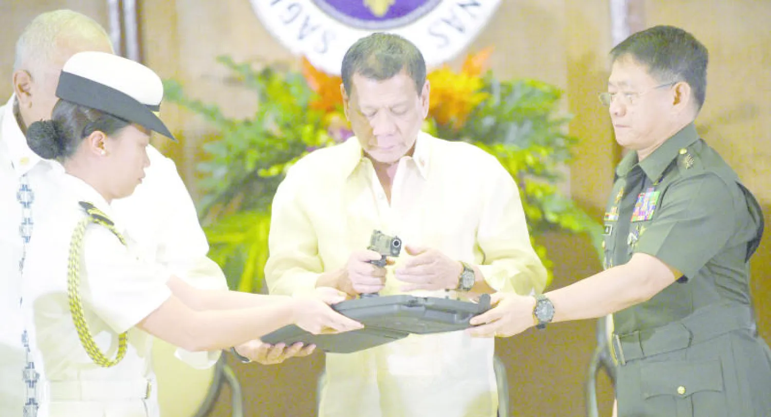 الرئيس الفلبيني رودريجو دوتيرتي يمسك بنسخة من مسدس «كاليبر 45» من المقرر توزيع 3 آلاف نسخة منه على رجال الشرطة في العاصمة مانيلا (أ.ف.ب)