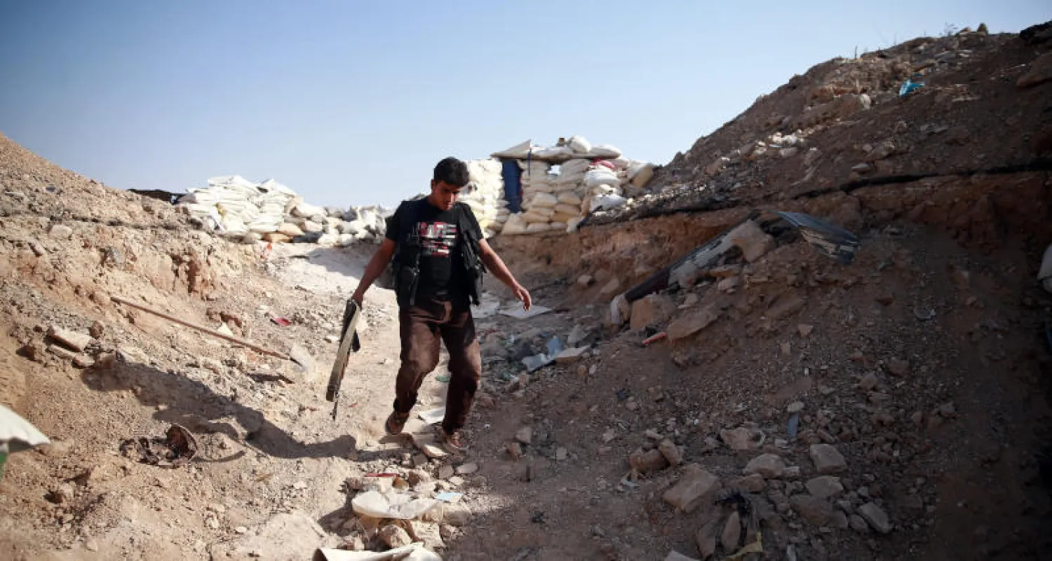 مقاتل يقترب من أكياس رمل مكدسة شرق مدينة الغوطة (رويترز)