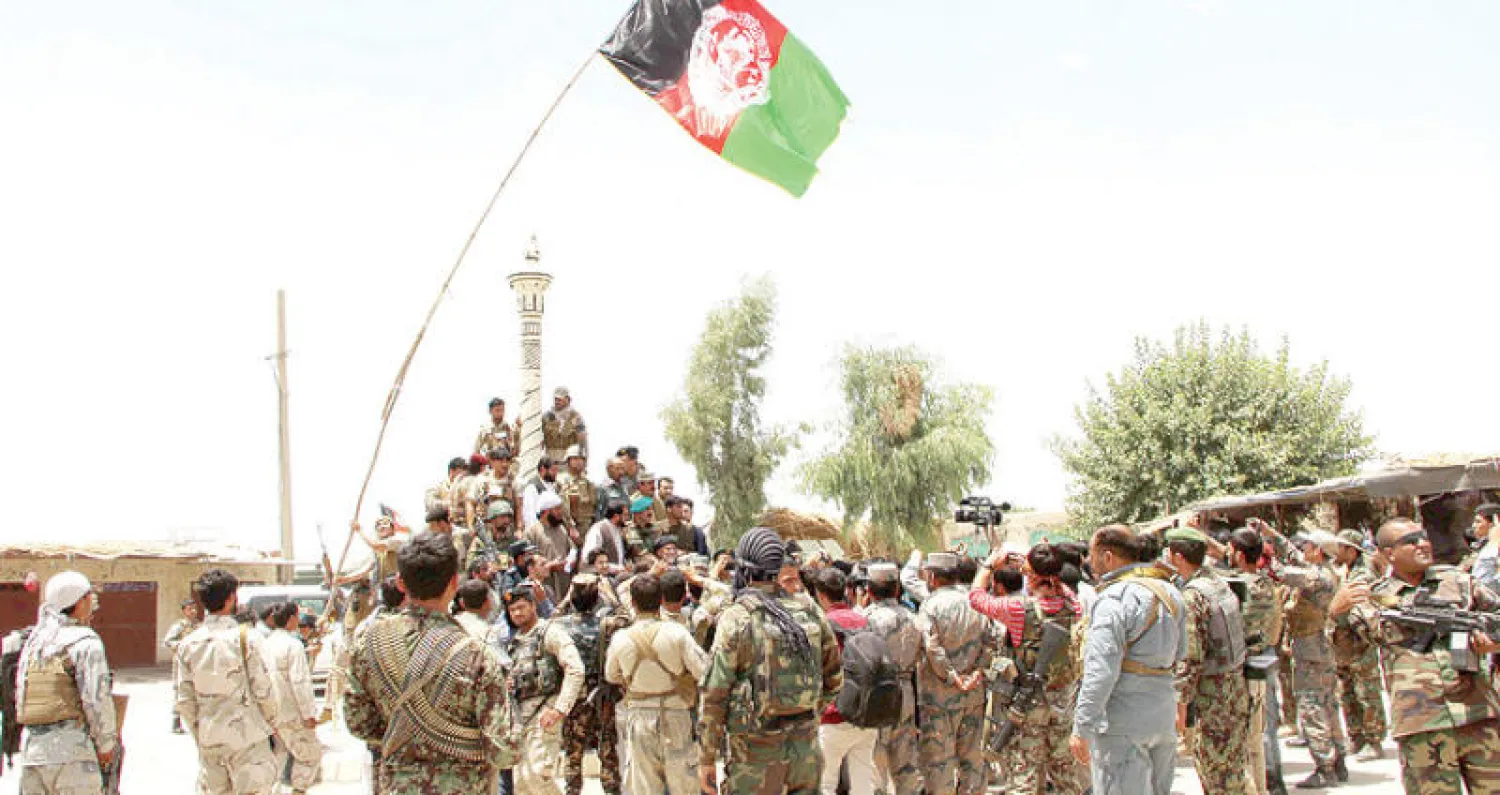 جنود حكوميون يرفعون العلم الأفغاني في ساحة مديرية نوى بإقليم هلمند بعد معارك دامت يومين ضد مقاتلي حركة طالبان (إ.ب.أ)