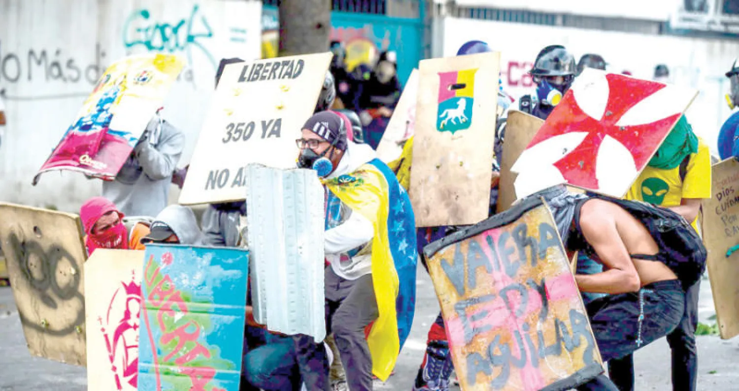 معارضون يصطدمون بقوات مكافحة الشغب في كراكاس أمس (أ.ف.ب)