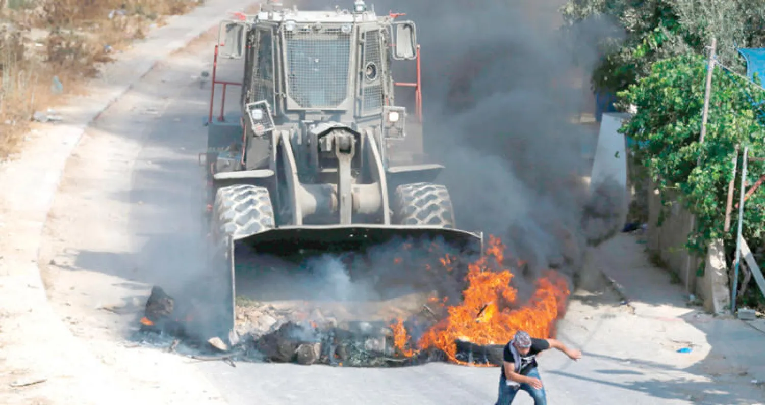 فلسطيني يقف متحديا دبابة إسرائيلية خلال المواجهات التي شهدتها أحياء قرية كوبر في رام الله أمس (أ.ف.ب)