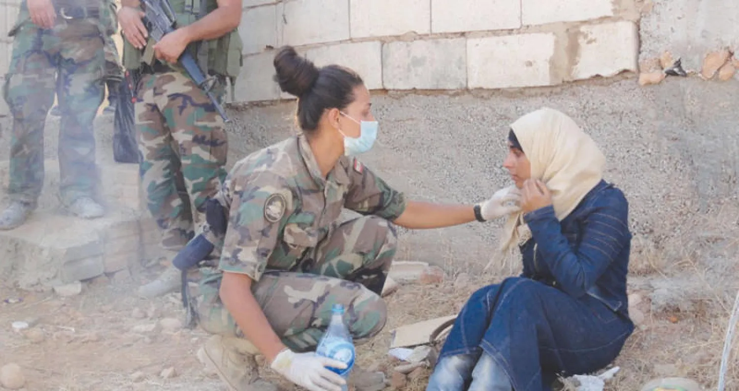 جندية في الجيش اللبناني تساعد لاجئة سورية في بلدة عرسال الحدودية مع سوريا (رويترز)