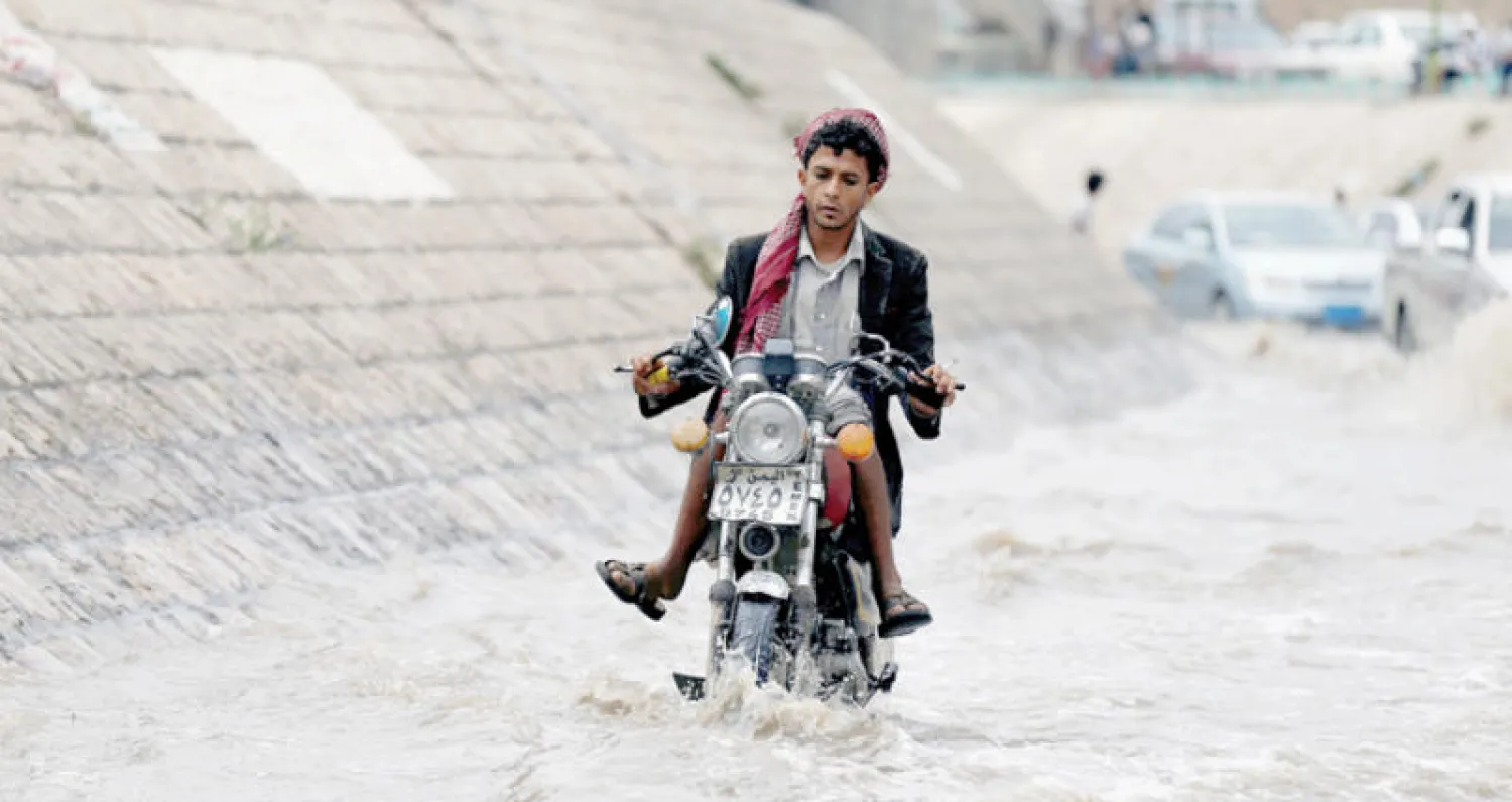 يمني يقود دراجته النارية وسط سيول ناجمة عن الأمطار في صنعاء أمس (رويترز)