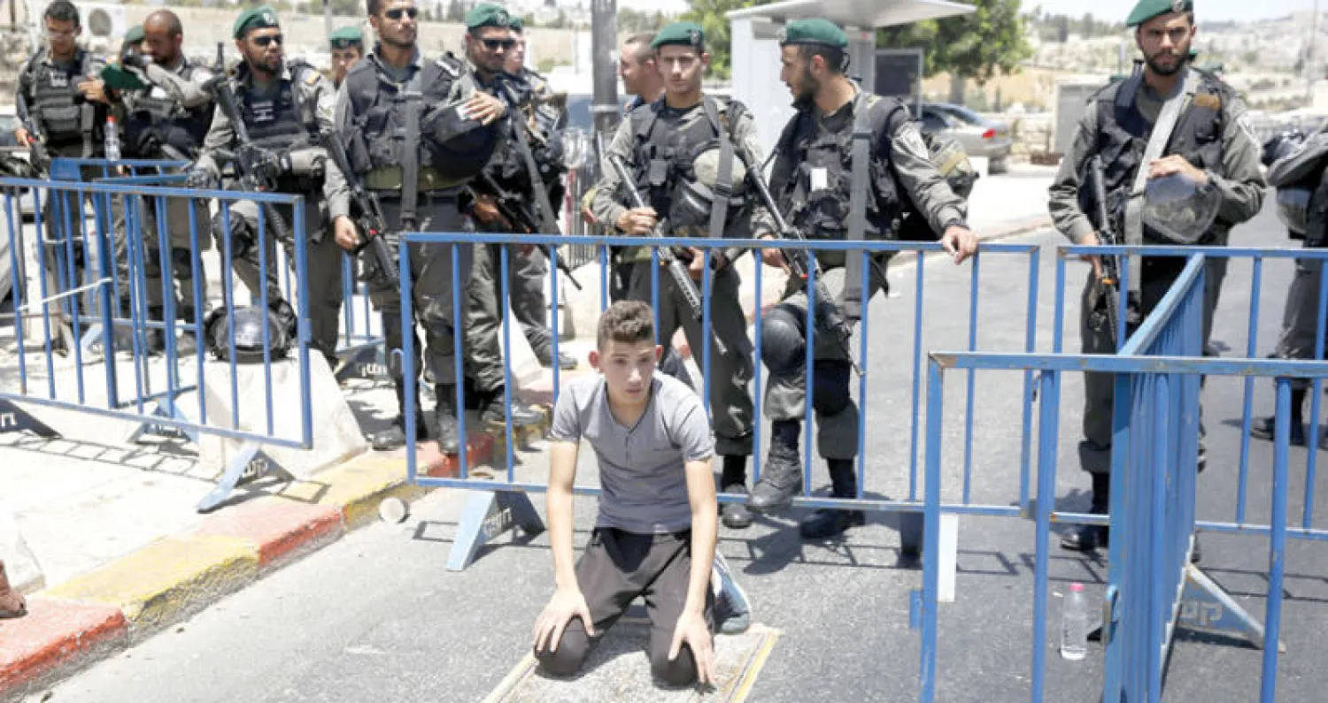 فتى فلسطيني يصلي أمس عند نقطة تفتيش إسرائيلية خارج القدس القديمة التي حولها الاحتلال إلى ثكنة عسكرية بنشر آلاف الجنود فيها (أ.ب)