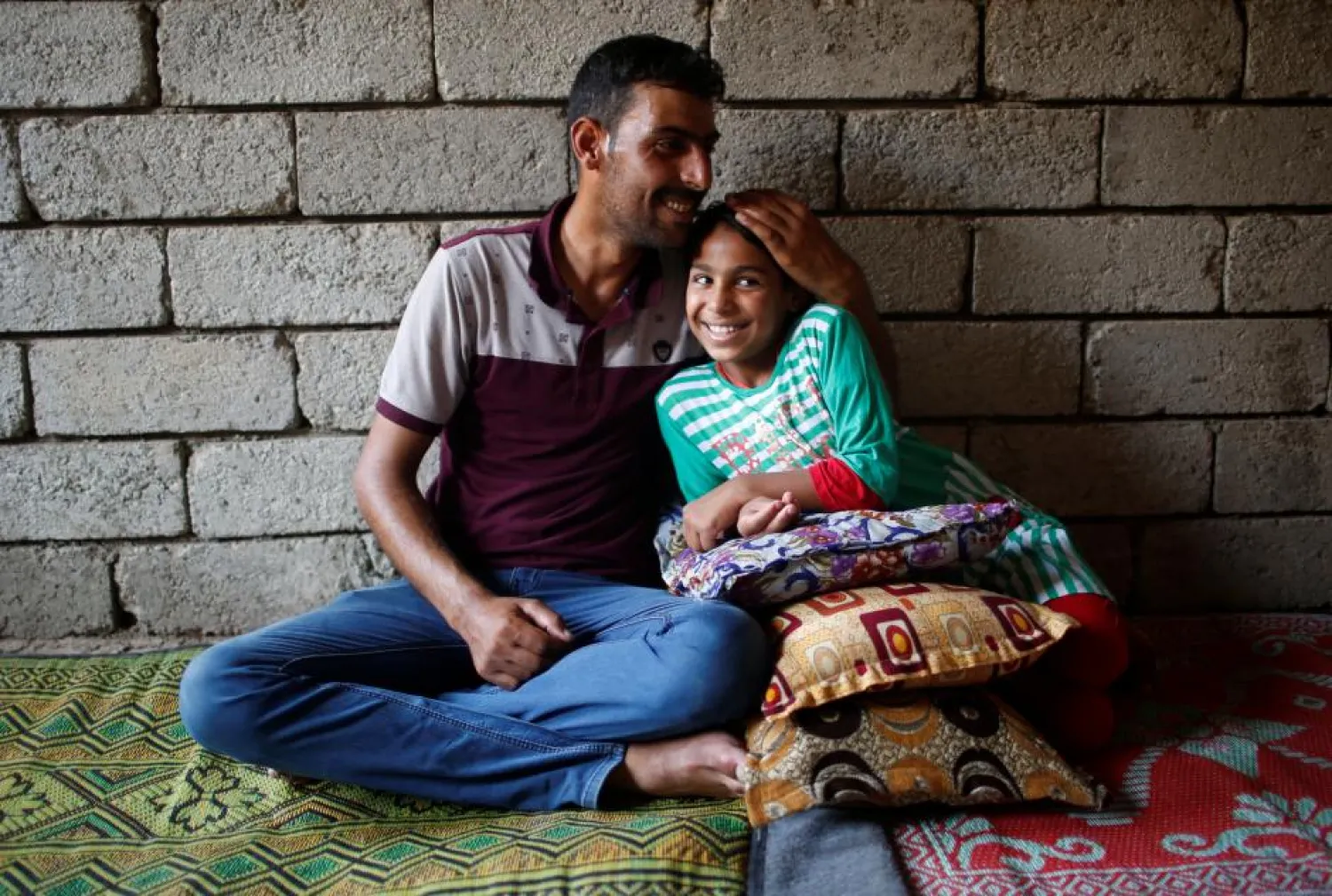 Nine-year-old Iraqi girl Meriam smiles as she sits next to her father Hassan in a house, east of Mosul, Iraq July 28, 2017. Picture taken July 28, 2017. REUTERS/Suhaib Salem