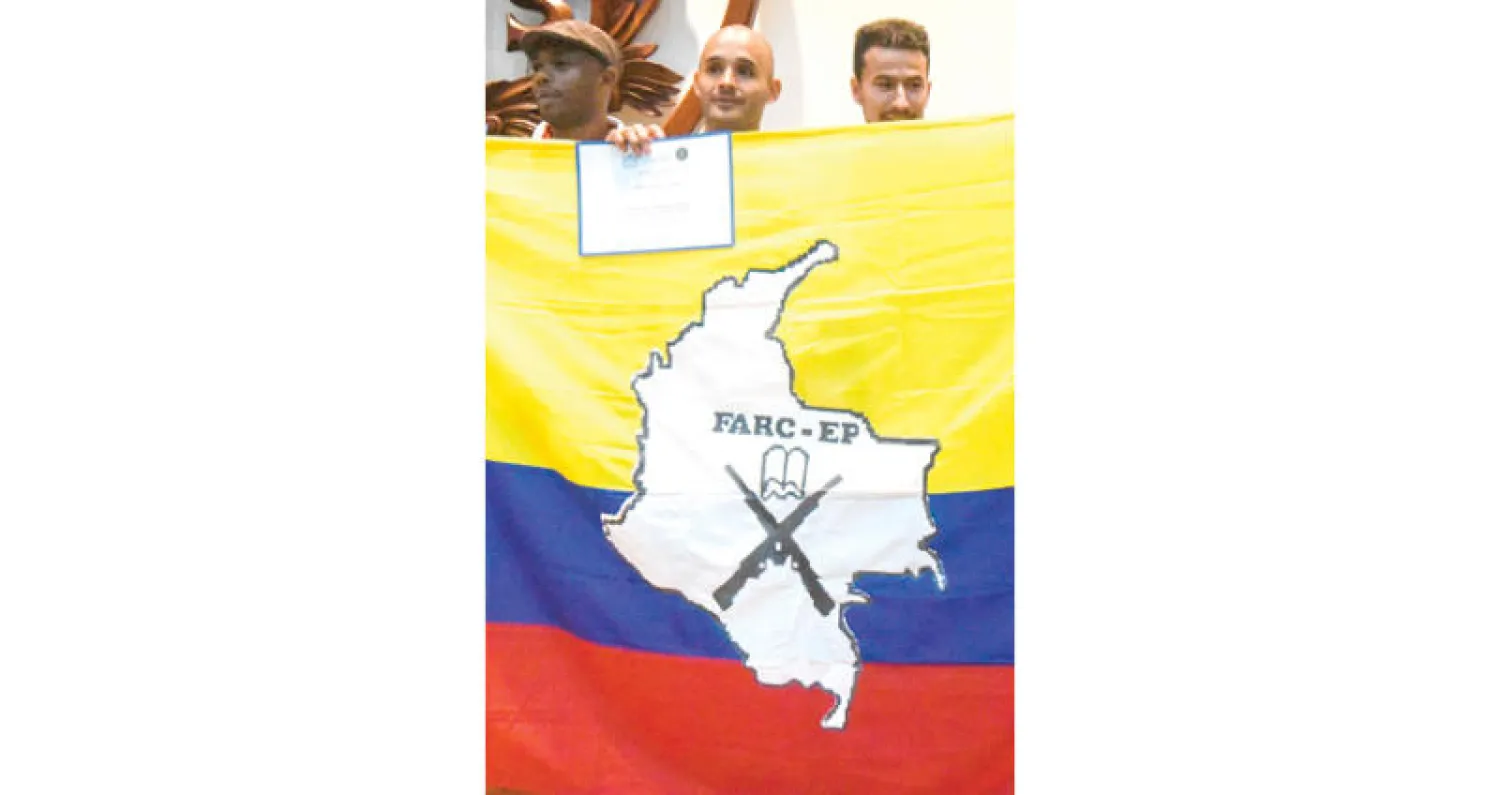 عضو سابق في {فارك} يحمل علم الحركة بعد تسلمه شهادة جامعية للانخراط في الحياة المدنية (أ.ف.ب)