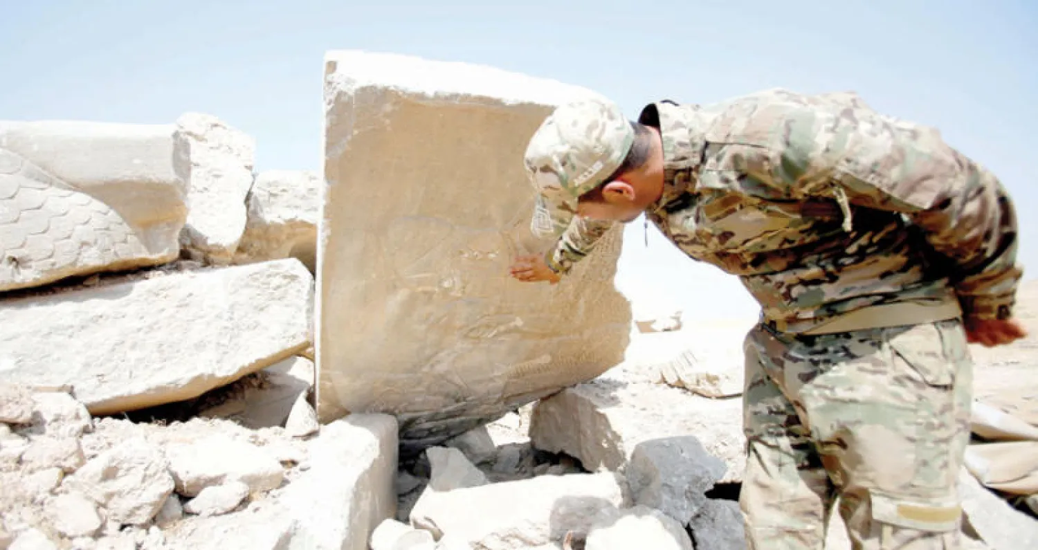 عنصر أمن عراقي يعاين آثاراً دمرها «داعش» في موقع النمرود جنوب الموصل أمس (رويترز)