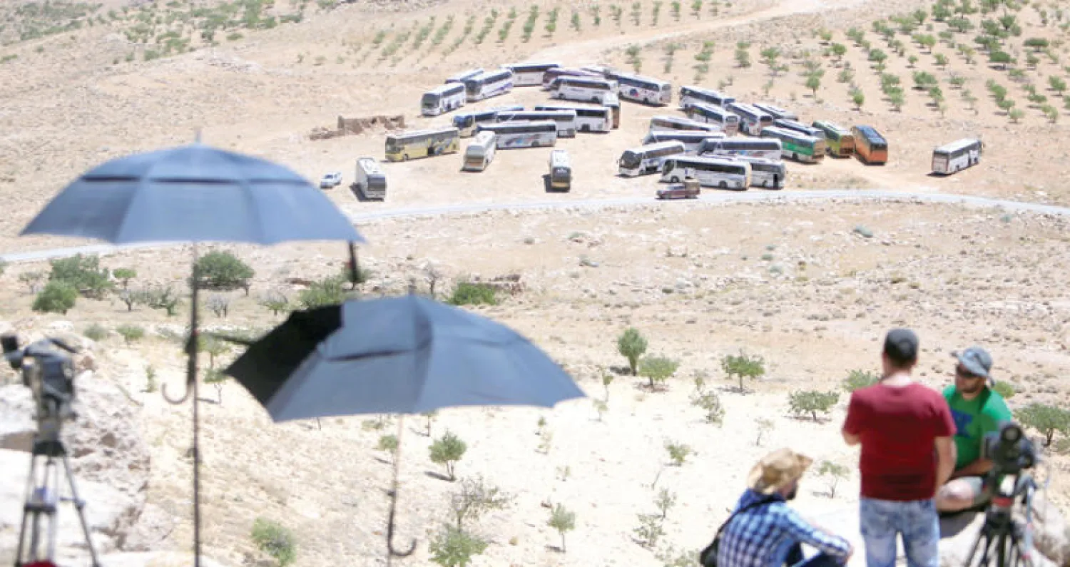 صحافيون ينتظرون انطلاق حافلات ستقل مقاتلي «النصرة» ومدنيين سوريين من جرود عرسال أول من أمس (رويترز)