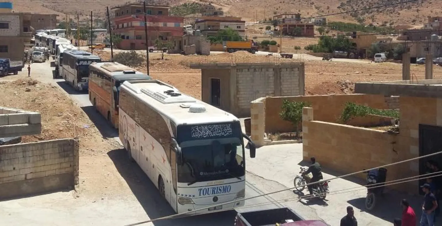 حافلات تقل سوريين بدأت تغادر مخيمات لاجئين في منطقة جرود عرسال الحدودية اللبنانية (أ.ف.ب)