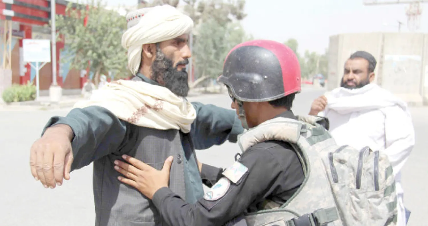جندي أفغاني يفتش رجلاً على طريق خارج ولاية قندهار عقب هجوم (إ.ب.أ)