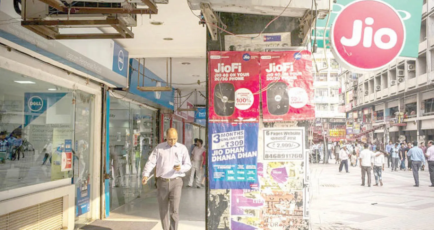 رجل يسير بقرب ملصق إعلاني لشبكة «ريلاينس جيو» للهواتف المحمولة في نيودلهي