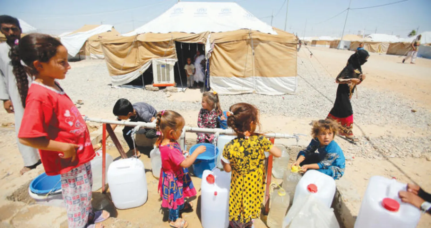 أطفال عراقيون ينتظرون دورهم لمل غالوناتهم بالماء في معسكر السالمية قرب الموصل (رويترز)