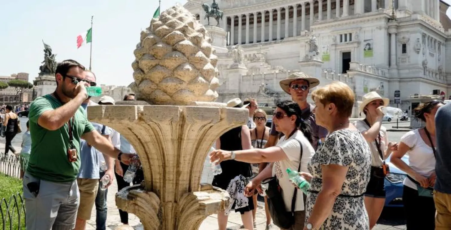أوروبيون يملأون زجاجاتهم بالماء من نافورة أمام نصب الجندي المجهول وسط روما (أ.ف.ب)