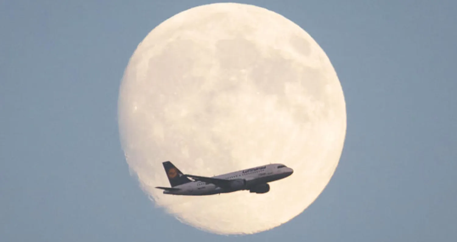 طائرة «لوفتهانزا» الألمانية تطير أمام قمر مكتمل في فرانكفورت  (أ.ف.ب)