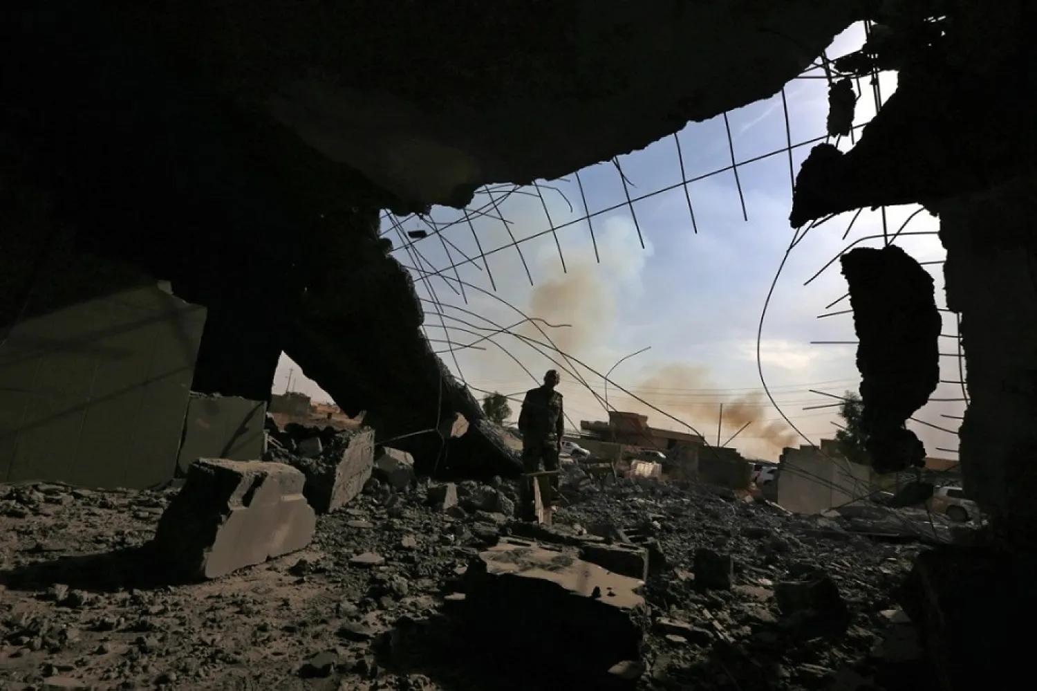 An Iraqi Kurdish Peshmerga fighter stands inside of a destroyed building on the frontline in the Shaqouli village, near Mosul, after recapturing it from ISIS in 2016. (AFP)