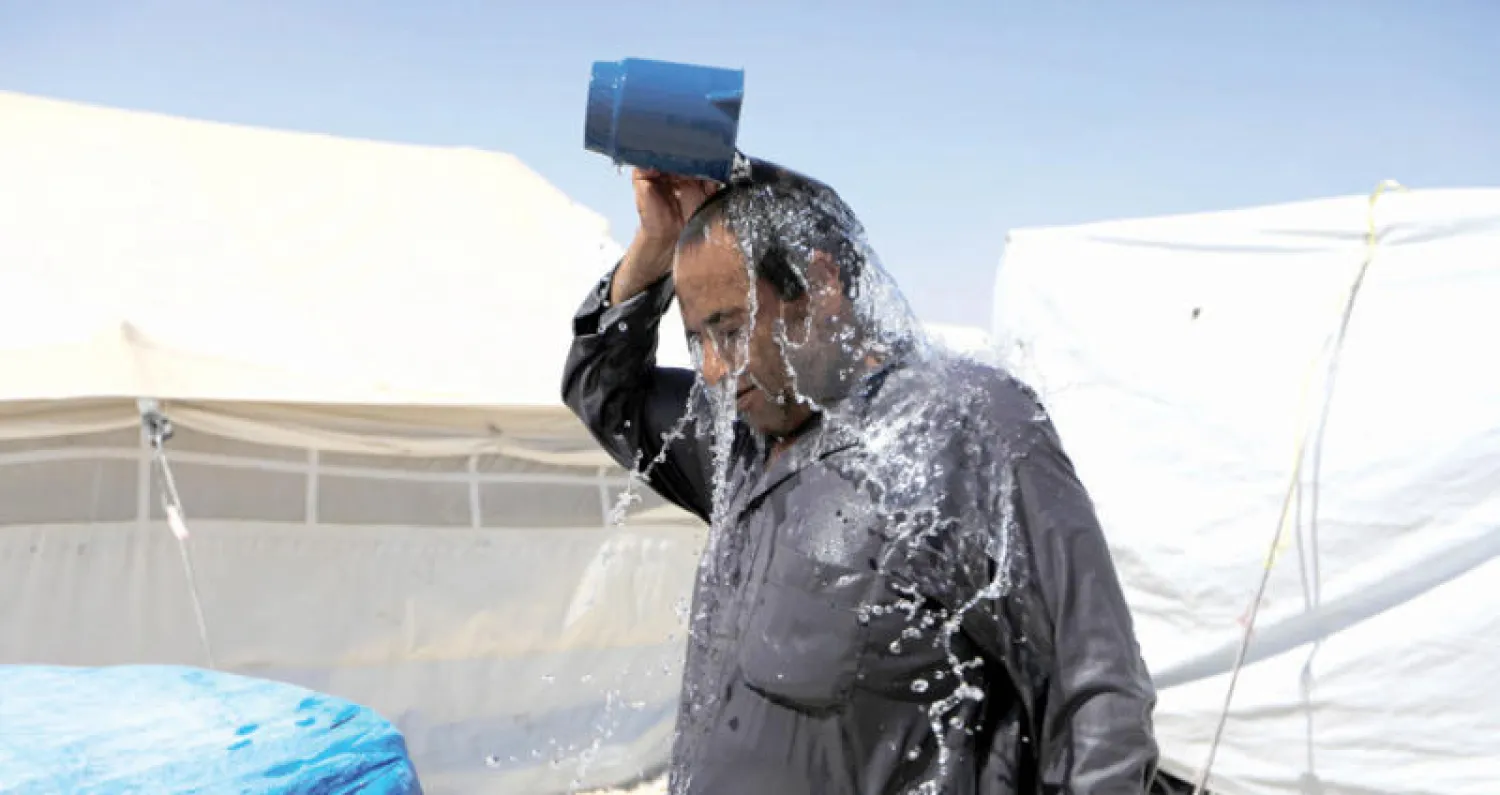 نازح من مدينة الرقة إلى مخيم عين عيسى يبرد نفسه من قيظ الحر بالماء (رويترز)
