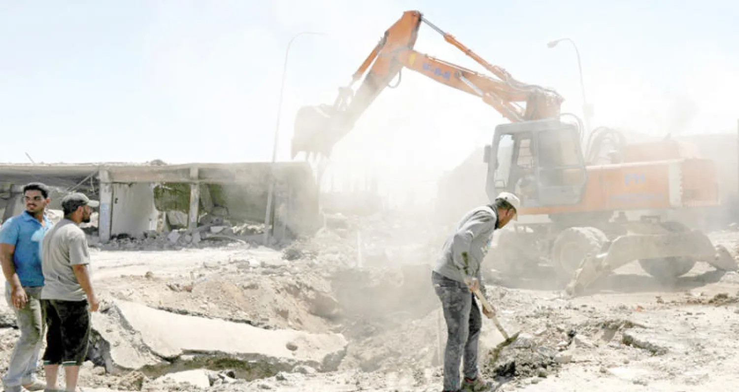 عمال يزيلون الأنقاض من أحد شوارع الموصل أول من أمس (رويترز)