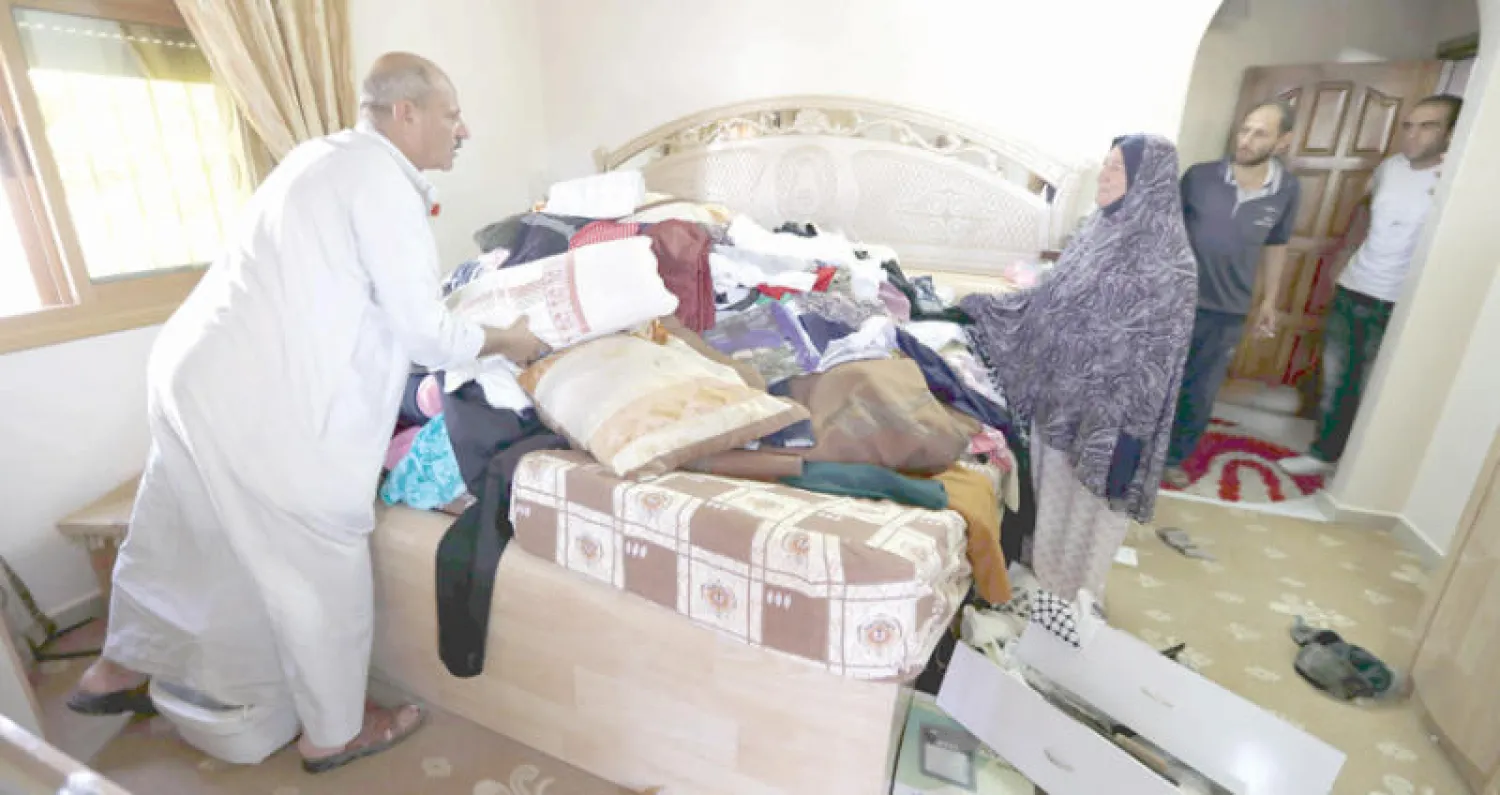 عائلة فلسطينية ترتب منزلها في الخليل بعدما داهمته قوات الاحتلال واعتقلت اثنين من قاطنيه أمس (إ.ب.أ)