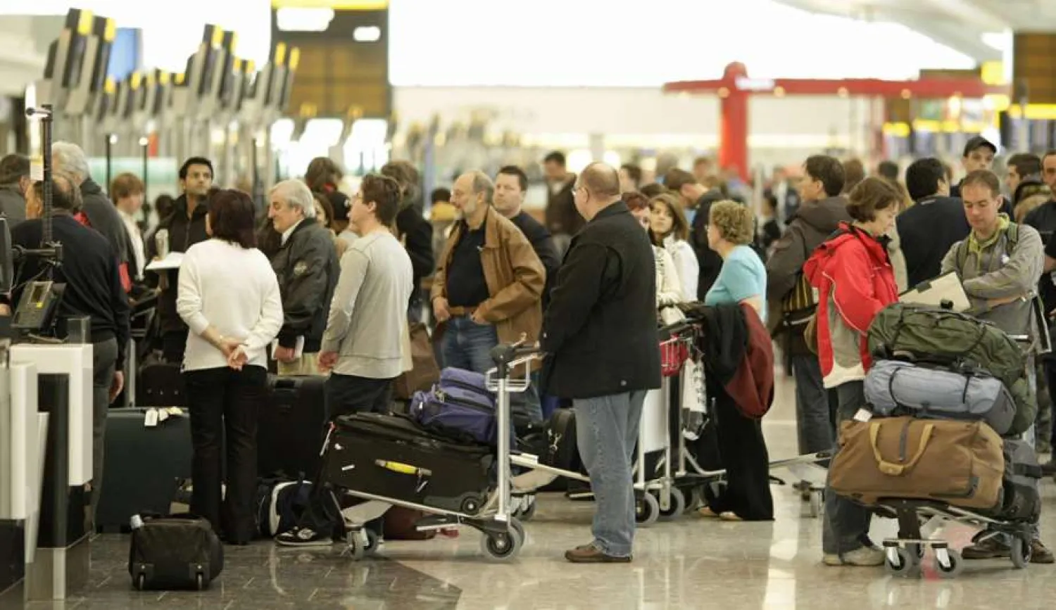 Travelers wait in line at an airport. (AFP)