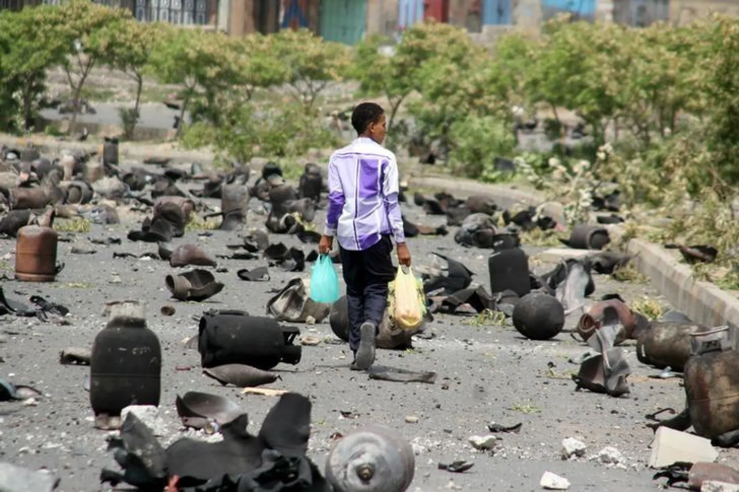 A boy walks on a street littered with cooking gas cylinders after a fire and explosions destroyed a nearby gas storage during clashes between fighters of the Popular Resistance Committees and Houthi men, in Yemen's southwestern city of Taiz July 19, 2015. REUTERS/Stringer/Files