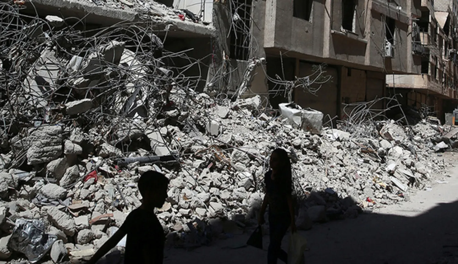 Children walk past the rubble of damaged buildings in Ein Tarma in the Damascus suburb of Eastern Ghouta, Syria, July 19, 2017.  (photo by REUTERS/Bassam Khabieh)