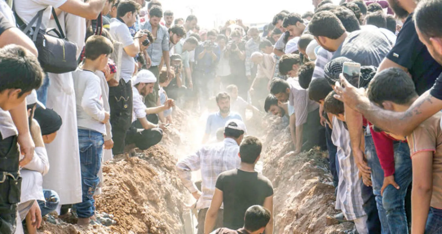 متطوعون في الدفاع المدني السوري يدفنون أمس في سرمين قرب إدلب 7 من رفاقهم قتلوا في هجوم على مقرهم (أ.ف.ب)