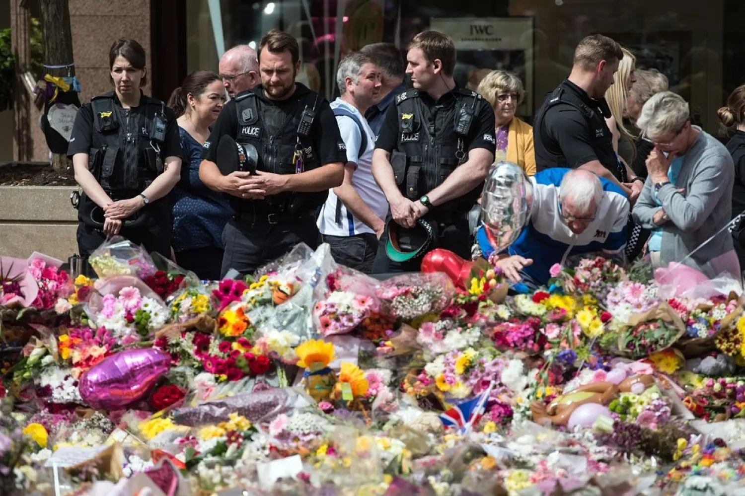 British police officers join the general public to view the flowers and messages left in honor of the victims of the terrorist attack in Manchester. (AFP)