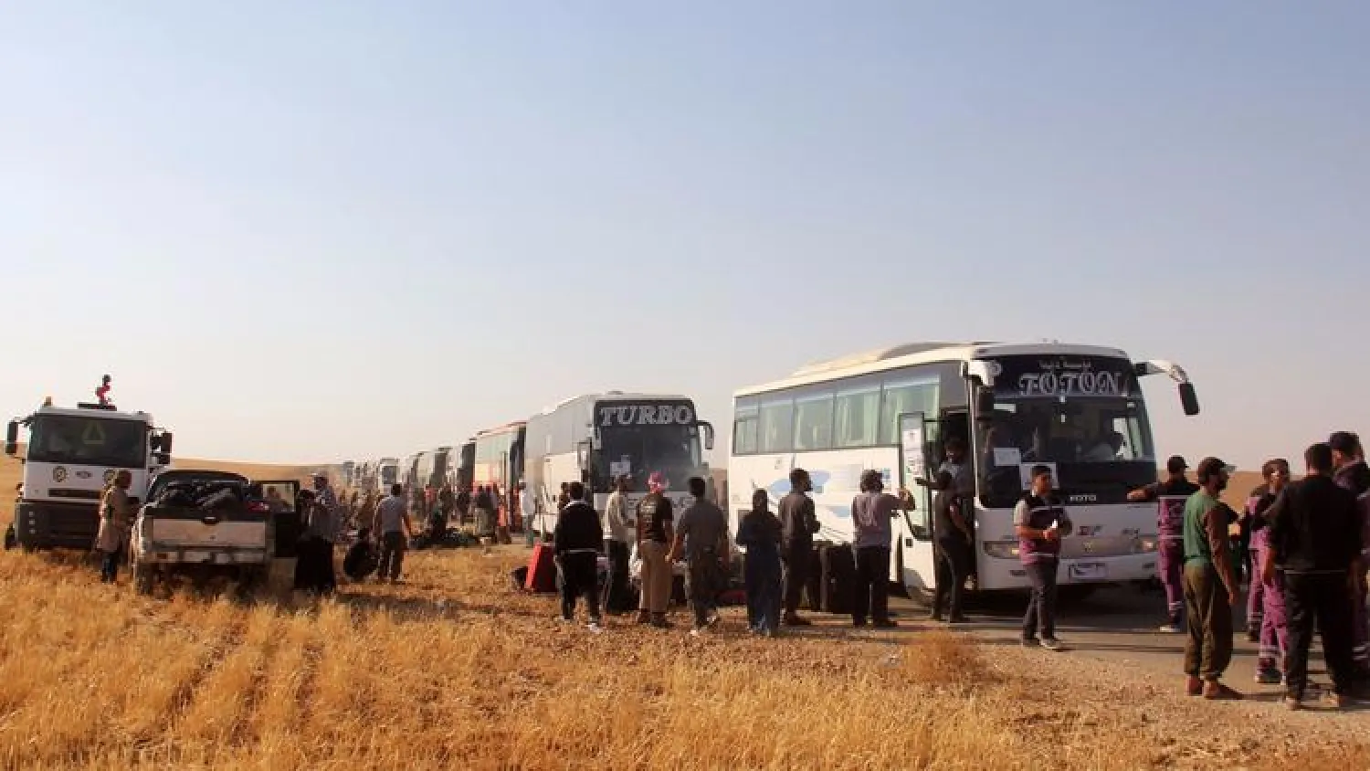 Syrian civilians and fighters who were evacuated from northeastern Lebanon gather near buses after crossing into the rebel-held area of Al-Saan in Syria on Aug. 3. (Omar Haj Kadour / Agence France-Presse / Getty Images)