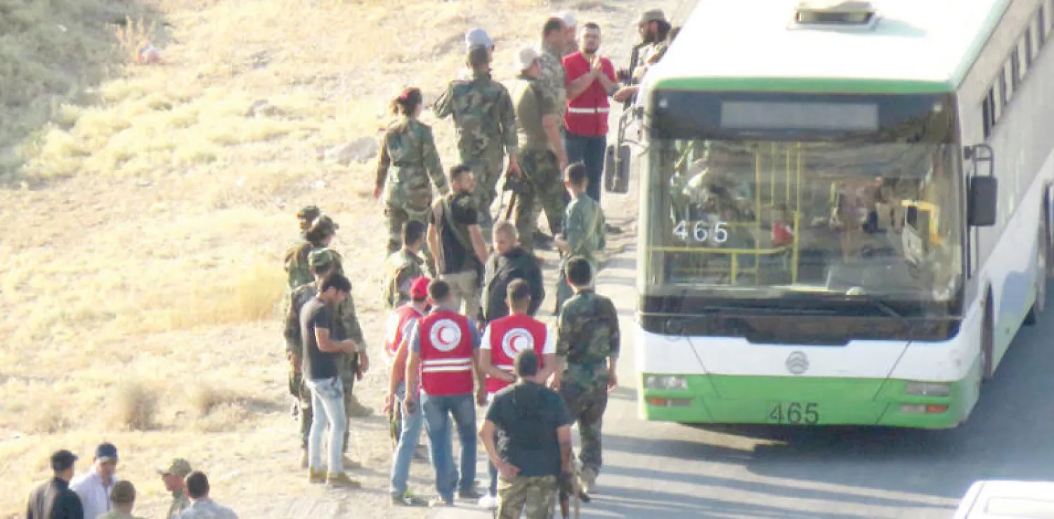 الصليب الأحمر في استقبال مقاتلي «سرايا أهل الشام» لدى وصولهم إلى الفليطة السورية قادمين من لبنان أول من أمس (أ.ف.ب)