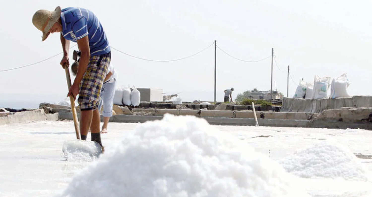 لبناني يعمل في أحواض تبخر الملح ببلدة أنفة الساحلية في شمال العاصمة بيروت (أ.ف.ب)