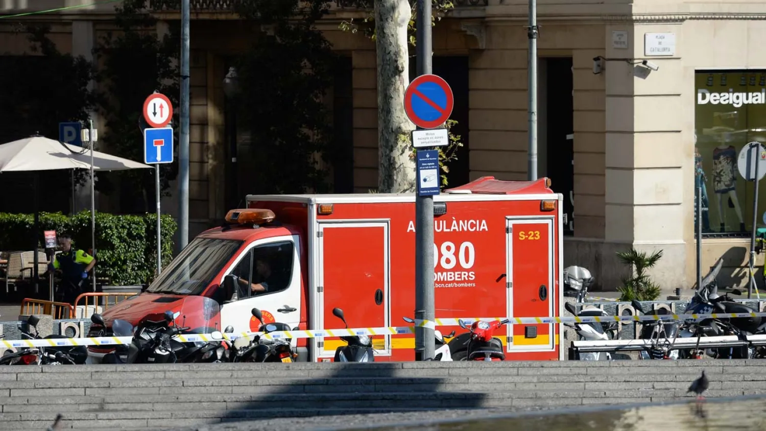 A policeman stands next to an ambulance after a van ploughed into the crowd on the Rambla in Barcelona on August 17, 2017. Josep LAGO / AFP 