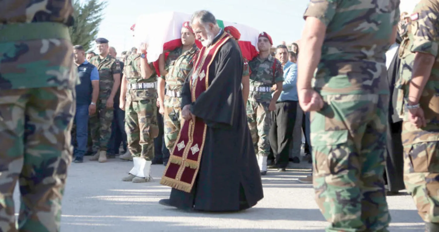 رجل دين مسيحي يقود جنازة إيلي فريجة في بلدة رعيت البقاعية والذي قتل في معارك الجيش اللبناني ضد داعش (أ.ف.ب)