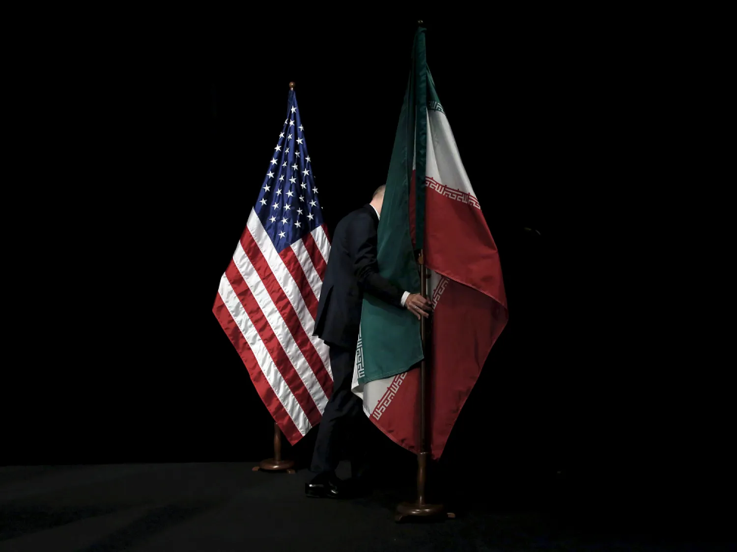 A staff member removes the Iranian flag from the stage after a group picture between Iranian officials and western powers during the Iran nuclear talks in 2015. (Reuters)
