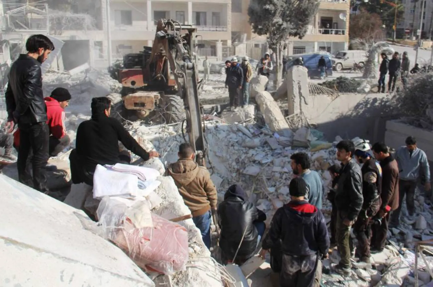 Syrian men and civil defense volunteers search for survivors amid the rubble of a building following airstrike on the northwestern city of Idlib. (AFP)
