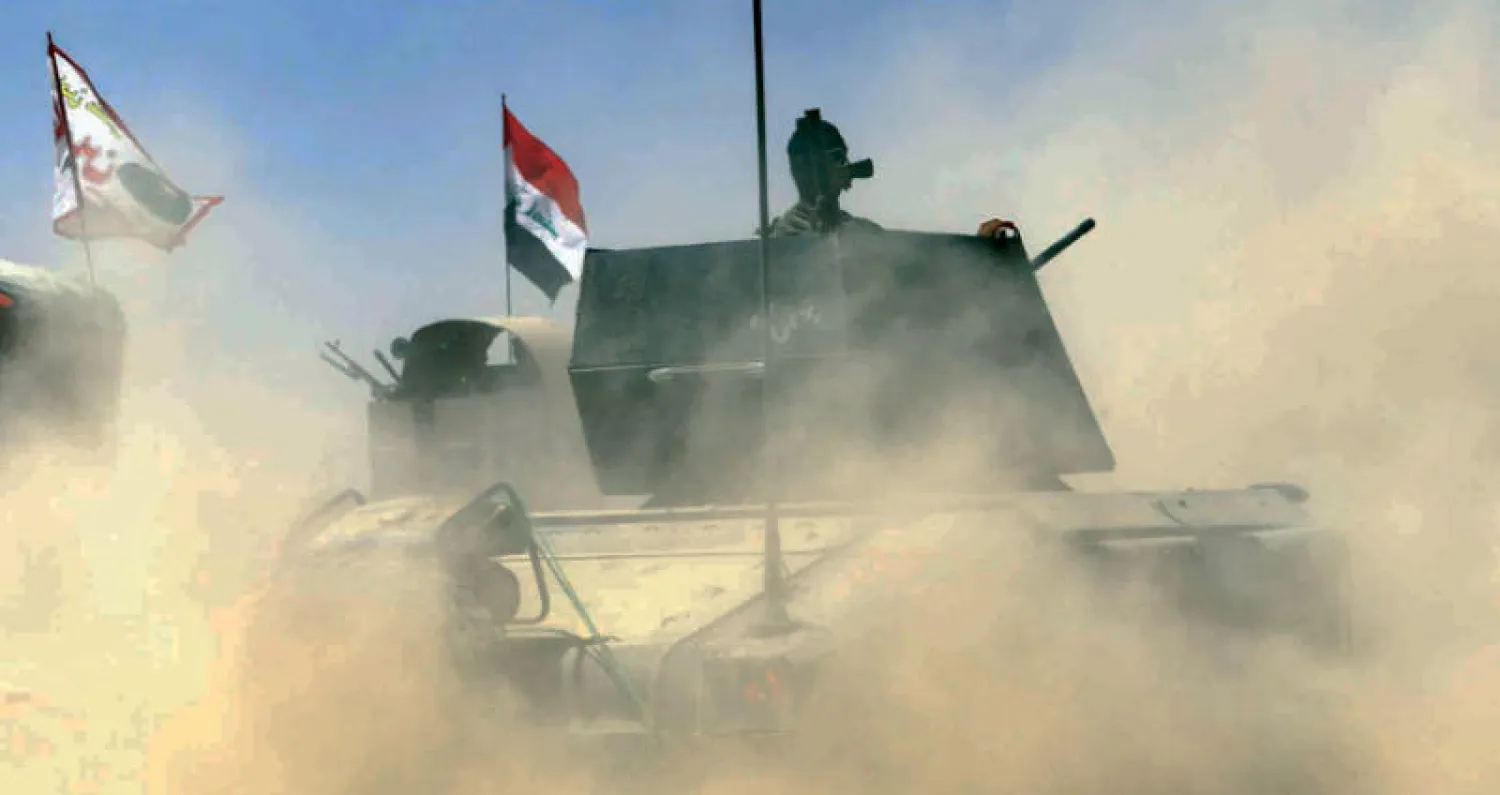 عربة عسكرية تشق طريقها وسط الغبار خلال المعارك مع «داعش» في تلعفر أمس (رويترز)