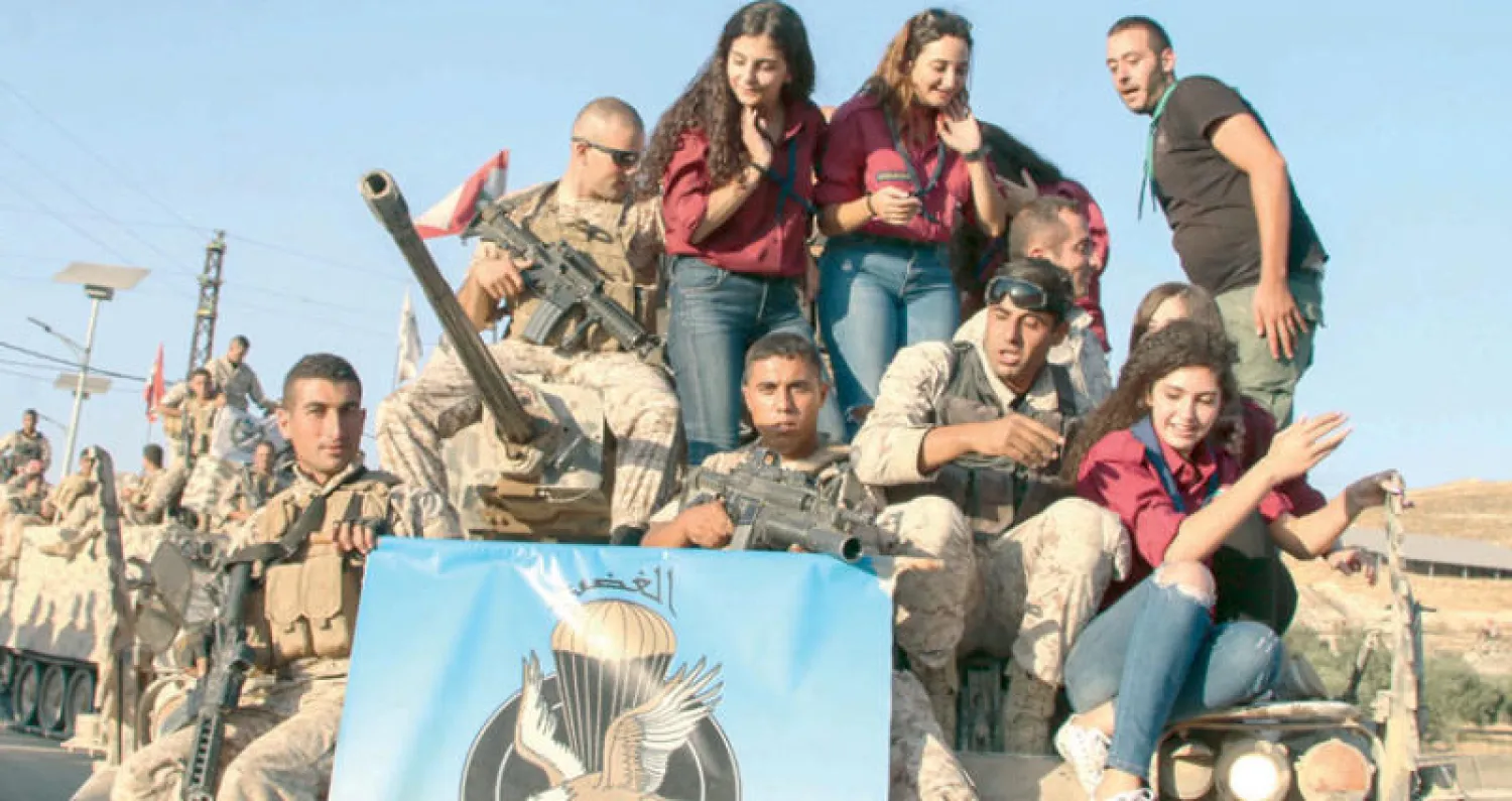 شباب لبنانيون فوق عربة عسكرية رفقة عناصر من الجيش اللبناني امس احتفالا بالانتصار على «داعش» (أ.ف.ب)