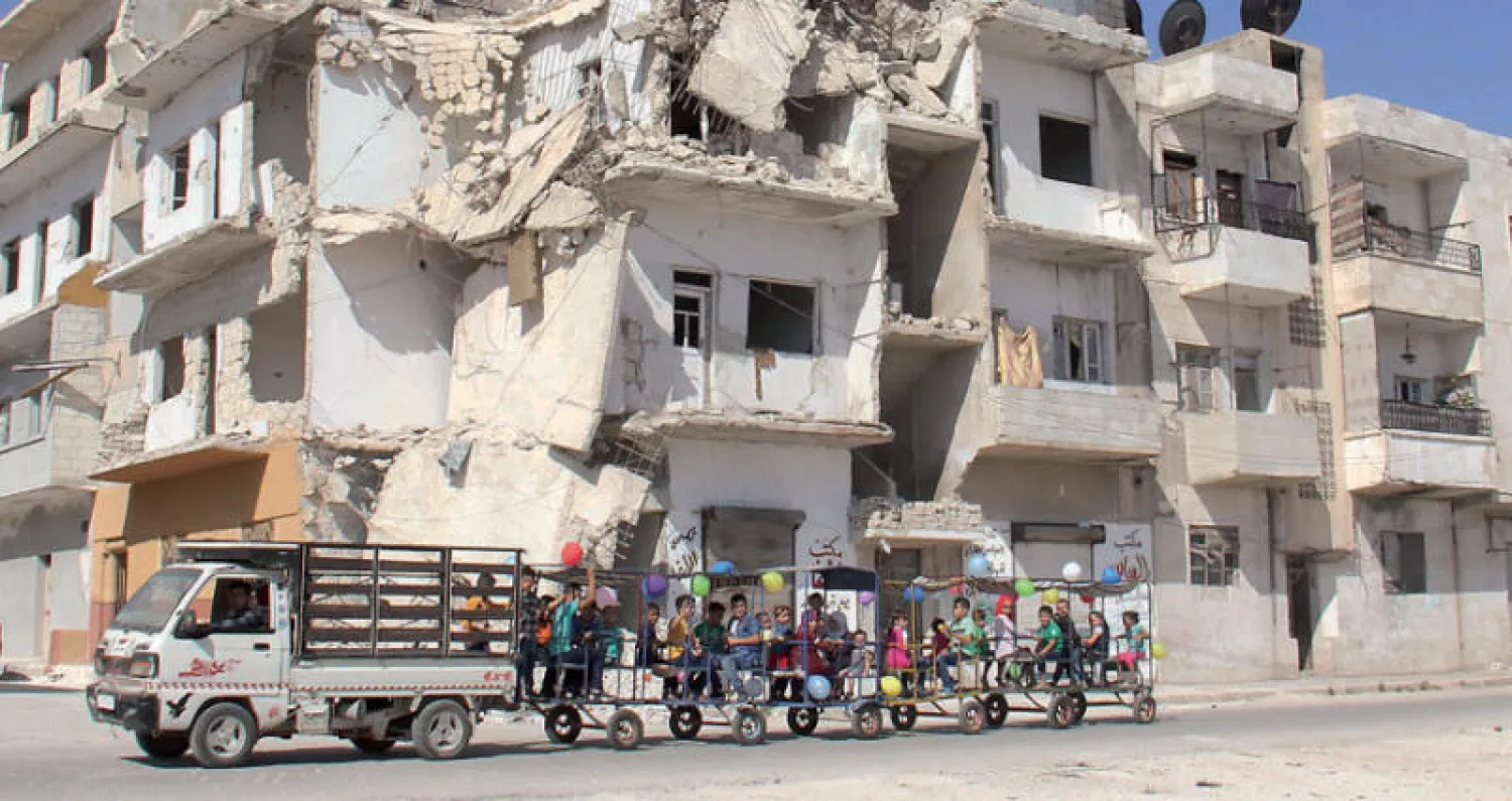 أطفال يحتفلون بأول أيام العيد في مدينة إدلب أمس (أ.ف.ب)