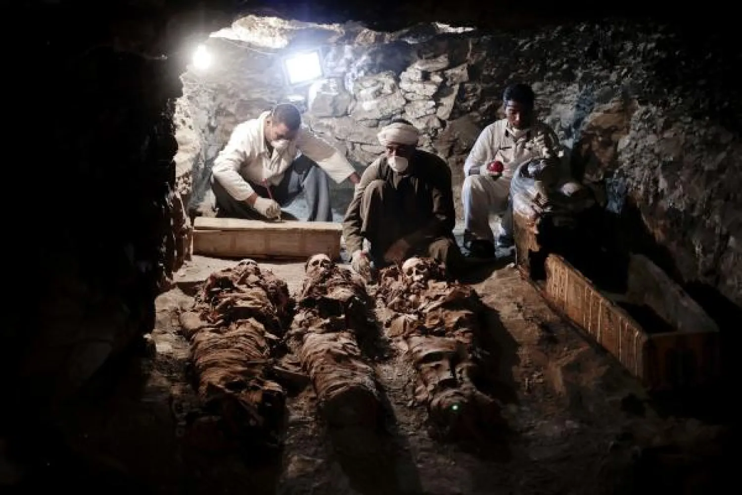 Archaeologists work on mummies found in the New Kingdom tomb that belongs to a royal goldsmith in a burial shaft, in Luxor, Egypt, Saturday, September 9, 2017. (AP)
