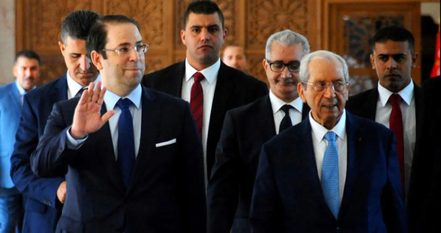 رئيس الحكومة التونسية الشاهد يحيّي مستقبليه لدى وصوله إلى البرلمان أمس (أ.ب)