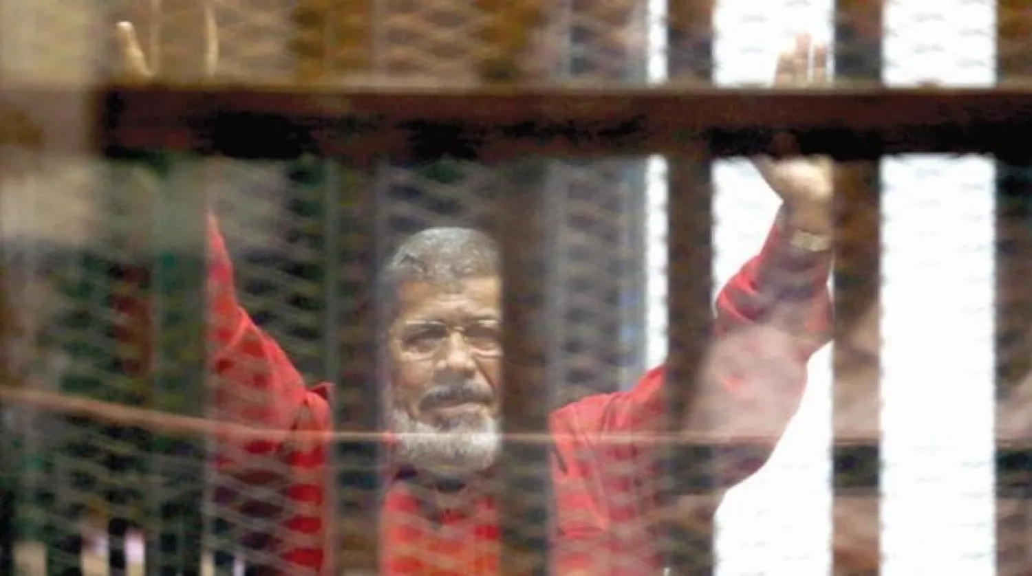 الرئيس المصري الأسبق محمد مرسي وراء القضبان بلباس أحمر عادة ما يرتديه المحكومون بالإعدام (رويترز)