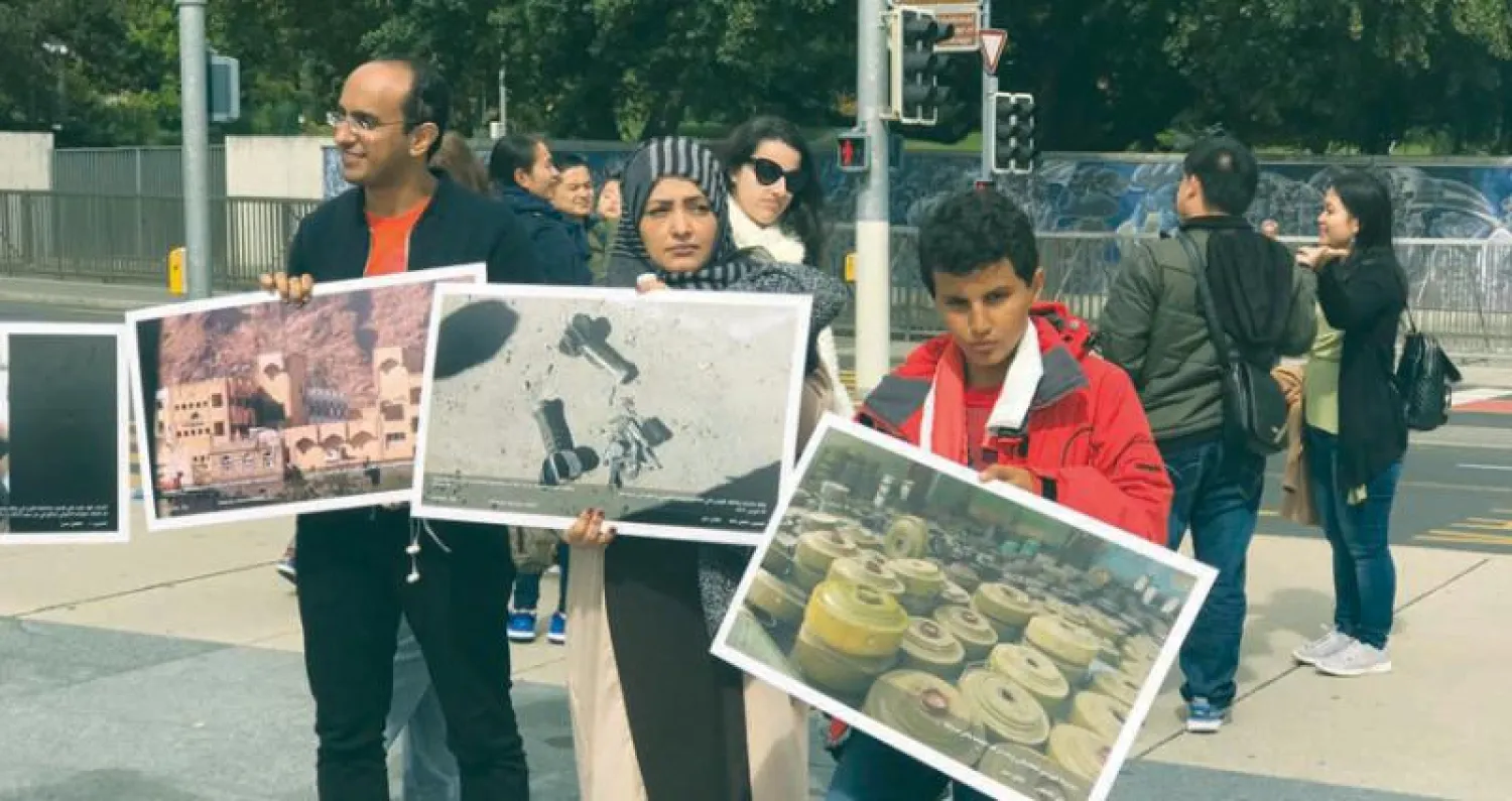 يمنيون يحملون صور الدمار الذي خلفه الحوثي وصالح باليمن في وقفة نظمها التحالف اليمني لرصد انتهاكات حقوق الإنسان بجنيف أمس («الشرق الأوسط»)